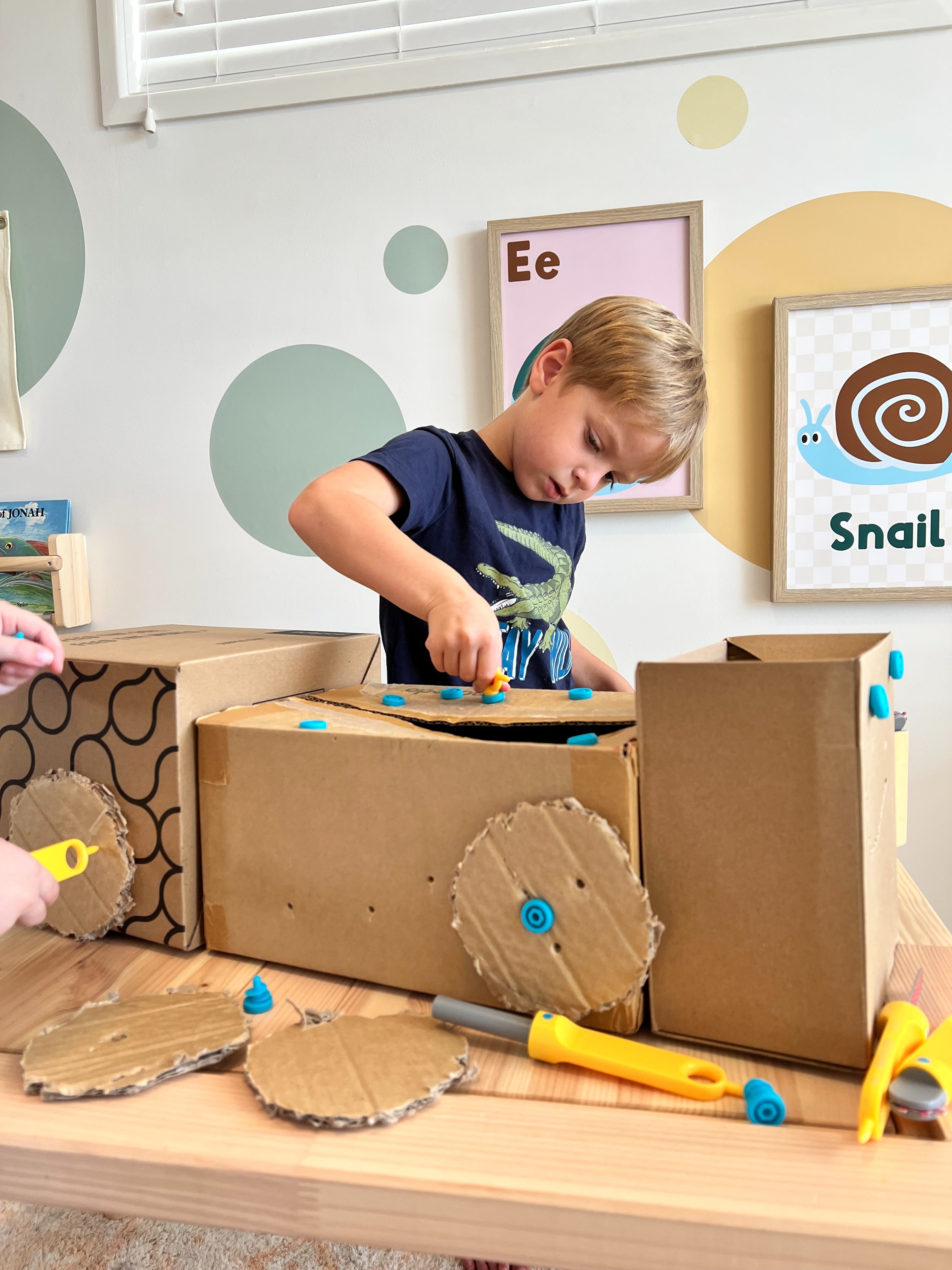 Enfant utilisant la Safe-Saw Makedo pour découper du carton